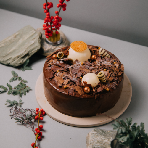 Chocolate cake with decorative toppings and red berries on a table.