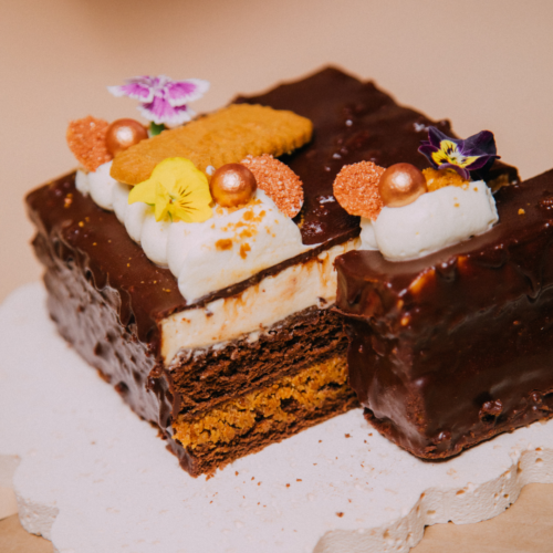 Chocolate cake with cream, edible flowers, and decorative toppings.