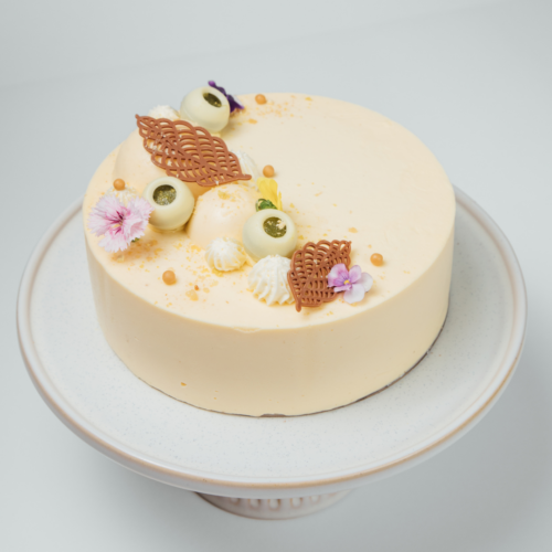 Elegant cake with decorative toppings on a white stand.