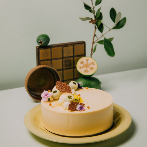 Decorative cake with flowers and fruit on a yellow plate.