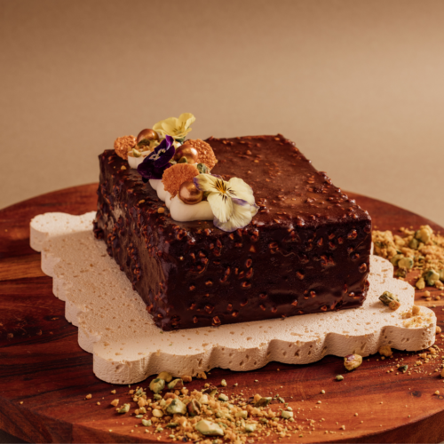Chocolate cake with floral decorations on a wooden board.