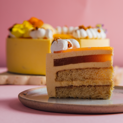 Slice of layered cake with frosting and fruit on a plate.