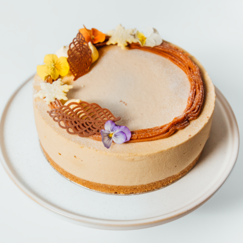 Creamy cake with floral and chocolate decorations on a white plate.