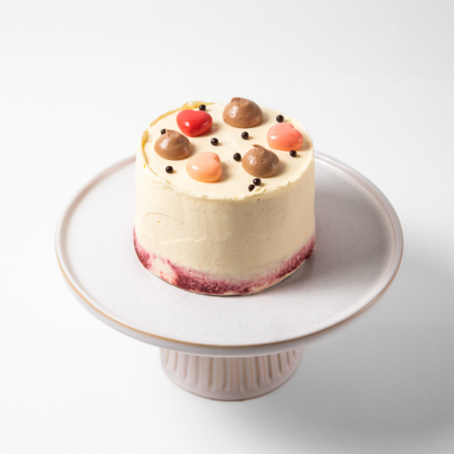 Small decorated cake on a white pedestal stand.