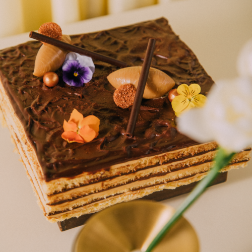 Chocolate layered cake with flowers and chocolate decorations on top.