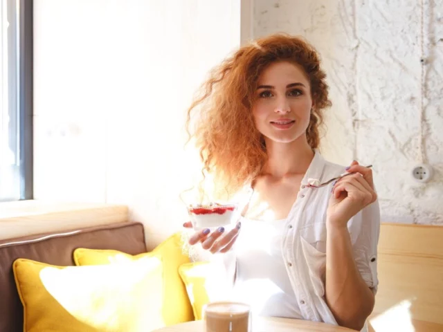 Woman enjoying panna cotta in a sunlit Italian café