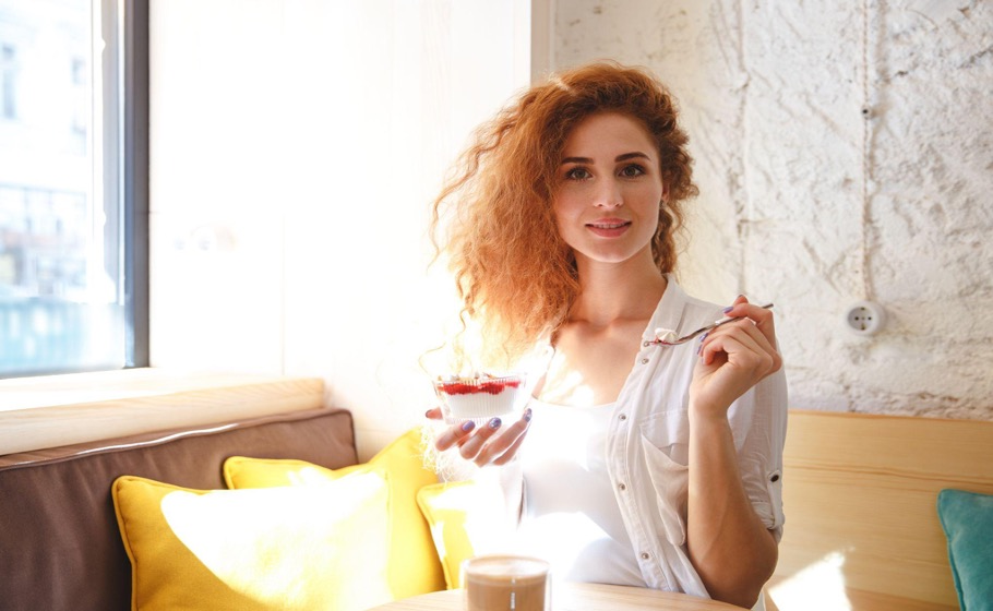 Woman enjoying panna cotta in a sunlit Italian café