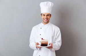Happy male chef holding a slice of cake