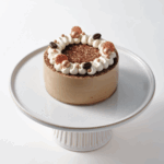 Tiramisu cake on a white pedestal stand.