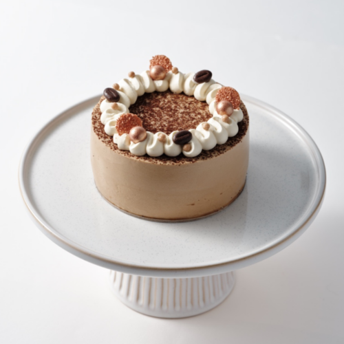 Tiramisu cake on a white pedestal stand.