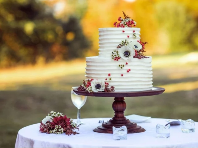 Two-tier cake with flowers on a wooden stand.