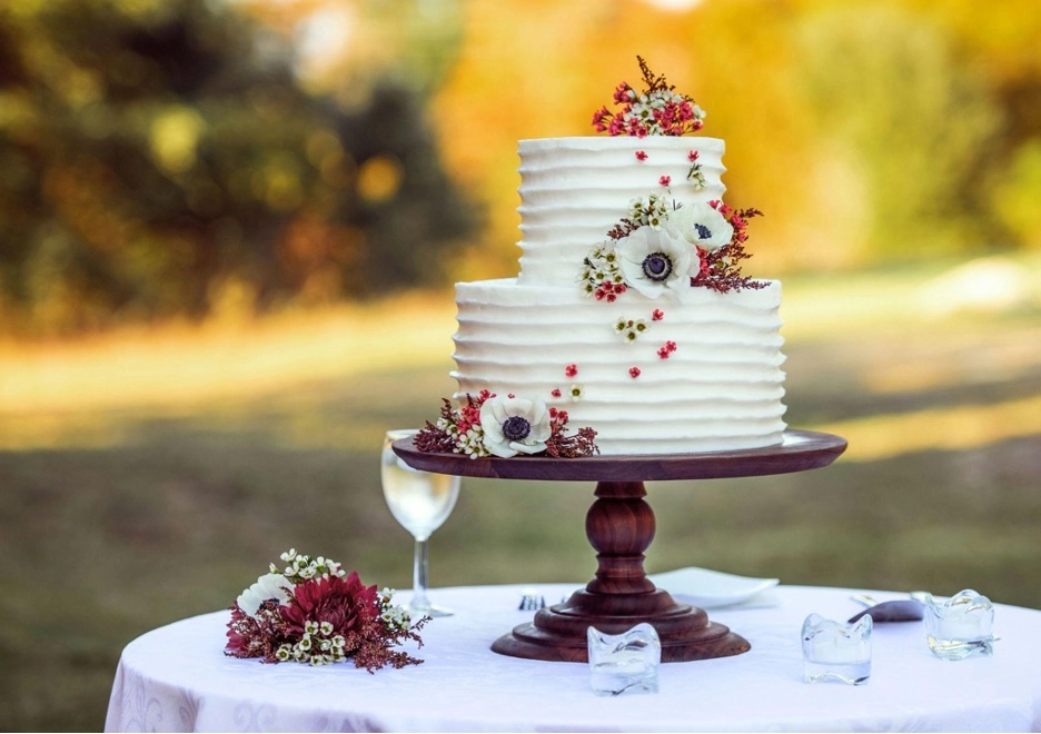 Two-tier cake with flowers on a wooden stand.