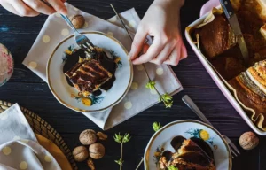 Person eating chocolate cake with walnuts on a table.