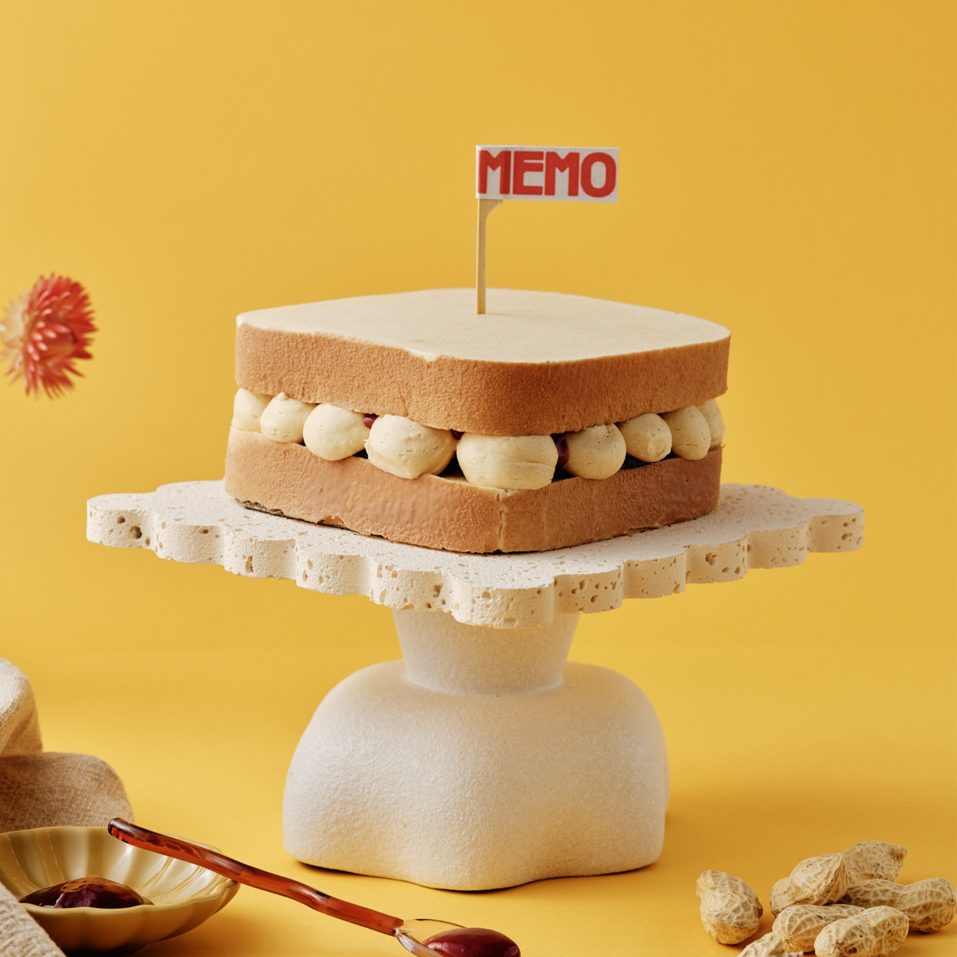 Cake resembling a sandwich on a stand with "MEMO" sign.