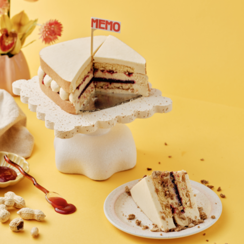 Cake slice on a plate, with whole cake on a stand.