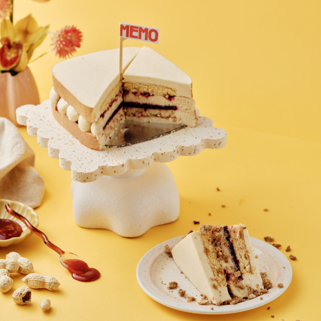 Cake slice on a plate, with whole cake on a stand.