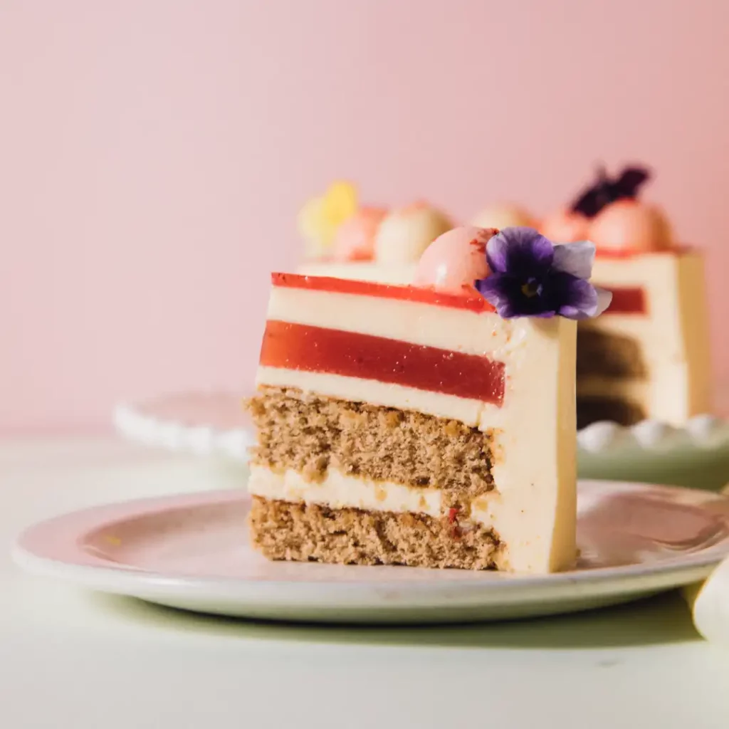 Slice of layered orange blossom cake with jelly, sponge layers, and edible flower 