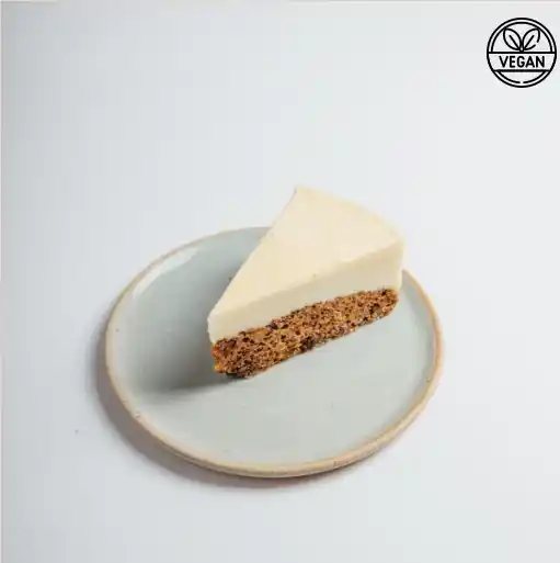 Slice of vegan cheesecake with a speckled nutty crust, served on a ceramic plate